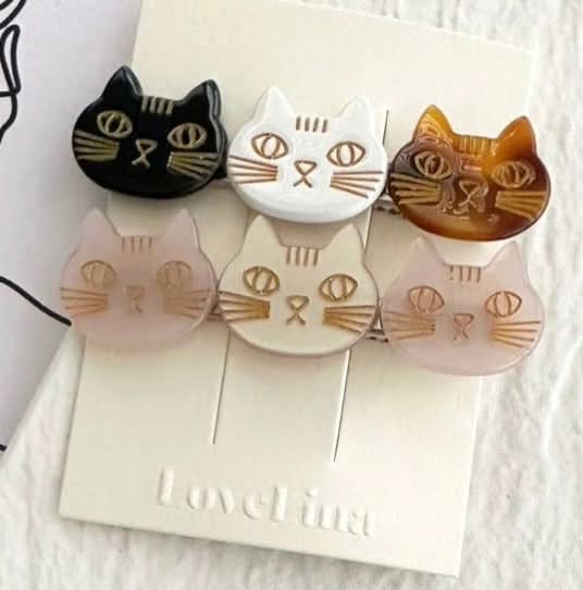 A pair of three colorful cats on a clip in a pack of two behind a white and purple background. 