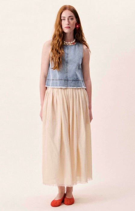 Woman wearing a denim top and beige skirt on a white background