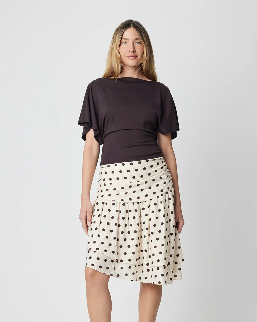Woman wearing a black top and polka dot skirt on a white background