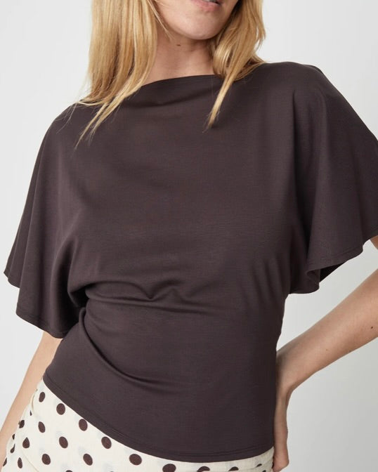 Woman wearing a dark brown top with a plain background