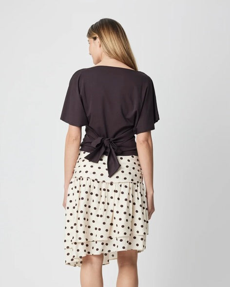 Woman wearing a black top and polka dot skirt on a white background