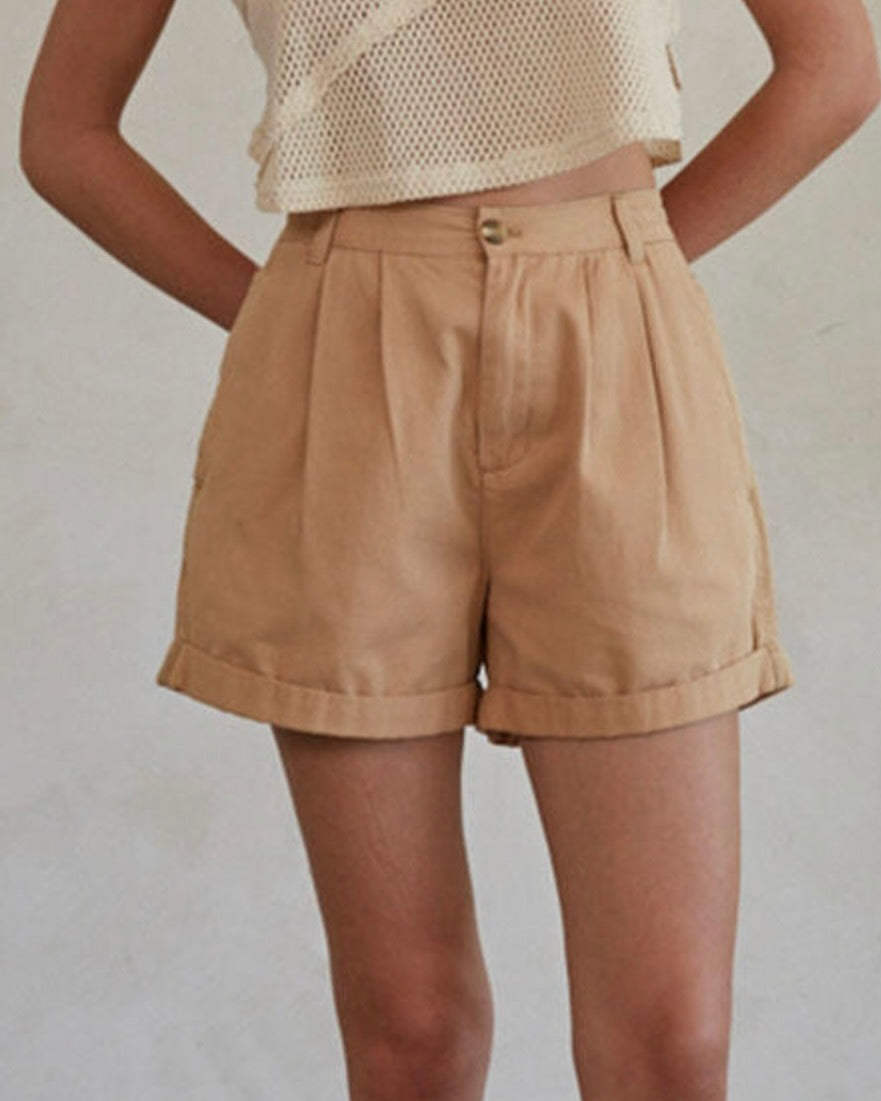 Person wearing beige shorts on a plain background