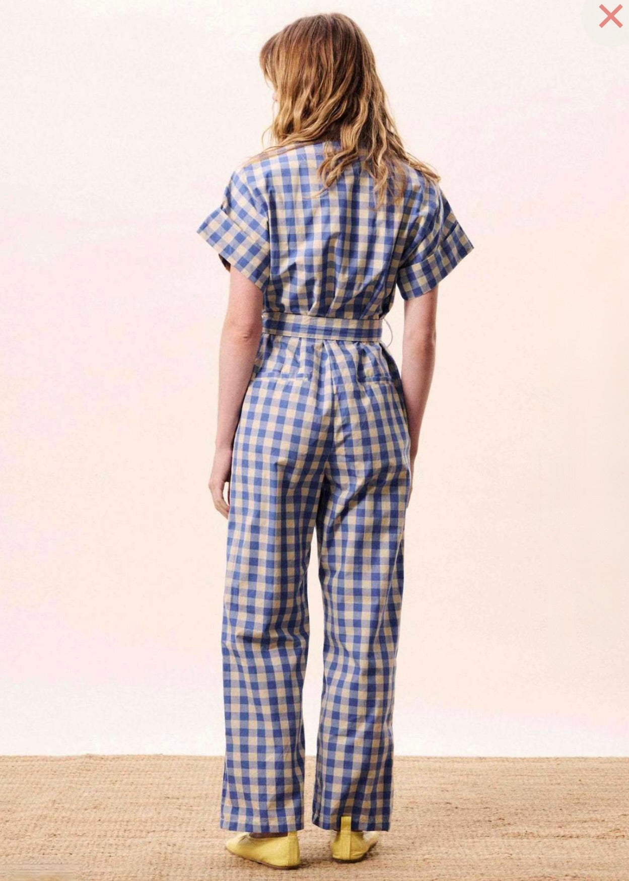 Person wearing a blue and white checkered jumpsuit on a plain background
