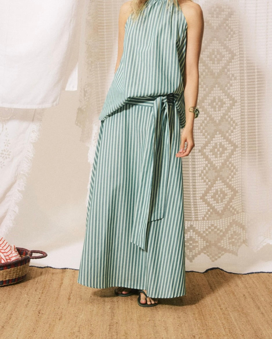 Person wearing a green and white striped dress against a textured white wall.