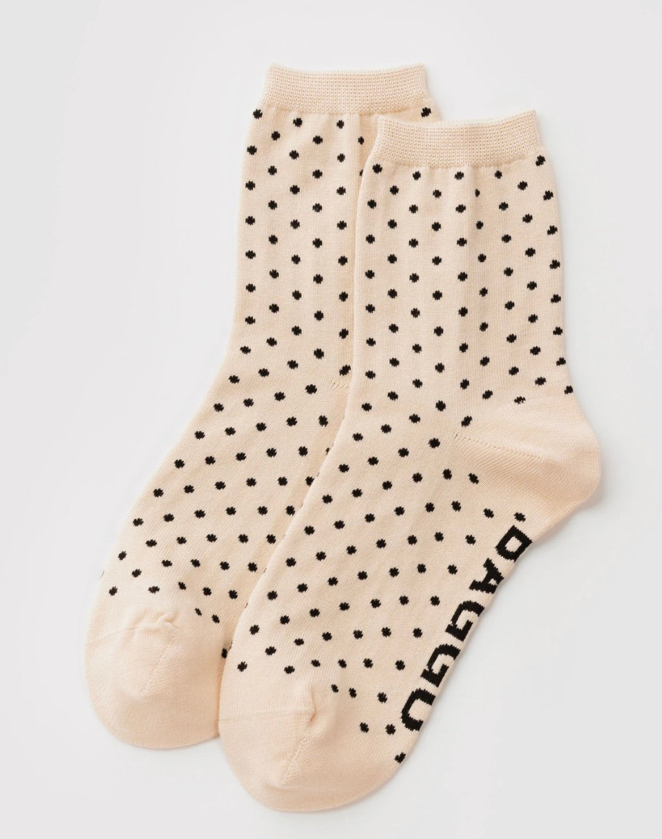 A pair of beige crew socks with a black polka dot pattern and the brand name 'DAGGU' printed in black on the sole, displayed against a light gray background.