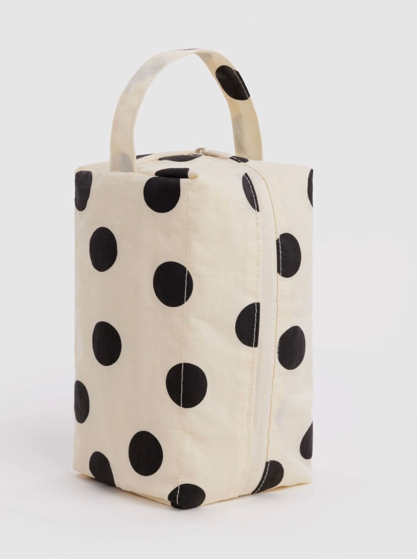 A cream-colored canvas lunch bag with a black polka dot pattern and a top handle, shown on a light gray background.