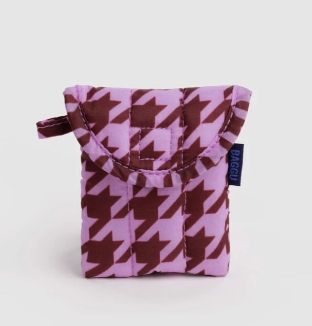 A small quilted pouch with a purple and brown houndstooth pattern, featuring a top handle and a small navy blue tag with the brand name BAGGU.