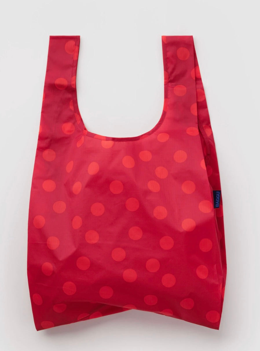 A reusable folding shopping bag in red with a pattern of darker red polka dots, shown against a plain light gray background.