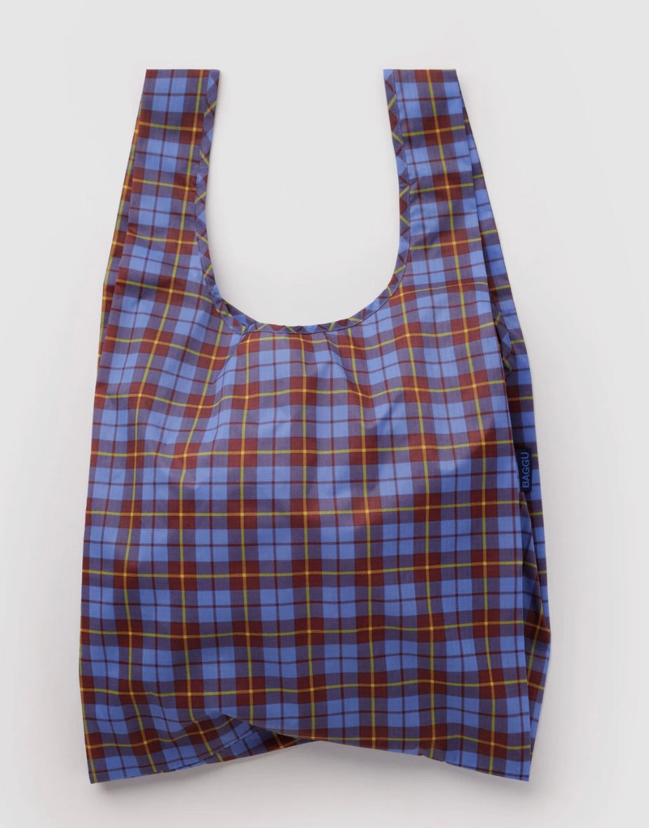 A reusable plastic shopping bag with a blue, brown, and yellow plaid pattern, shown against a plain light gray background.