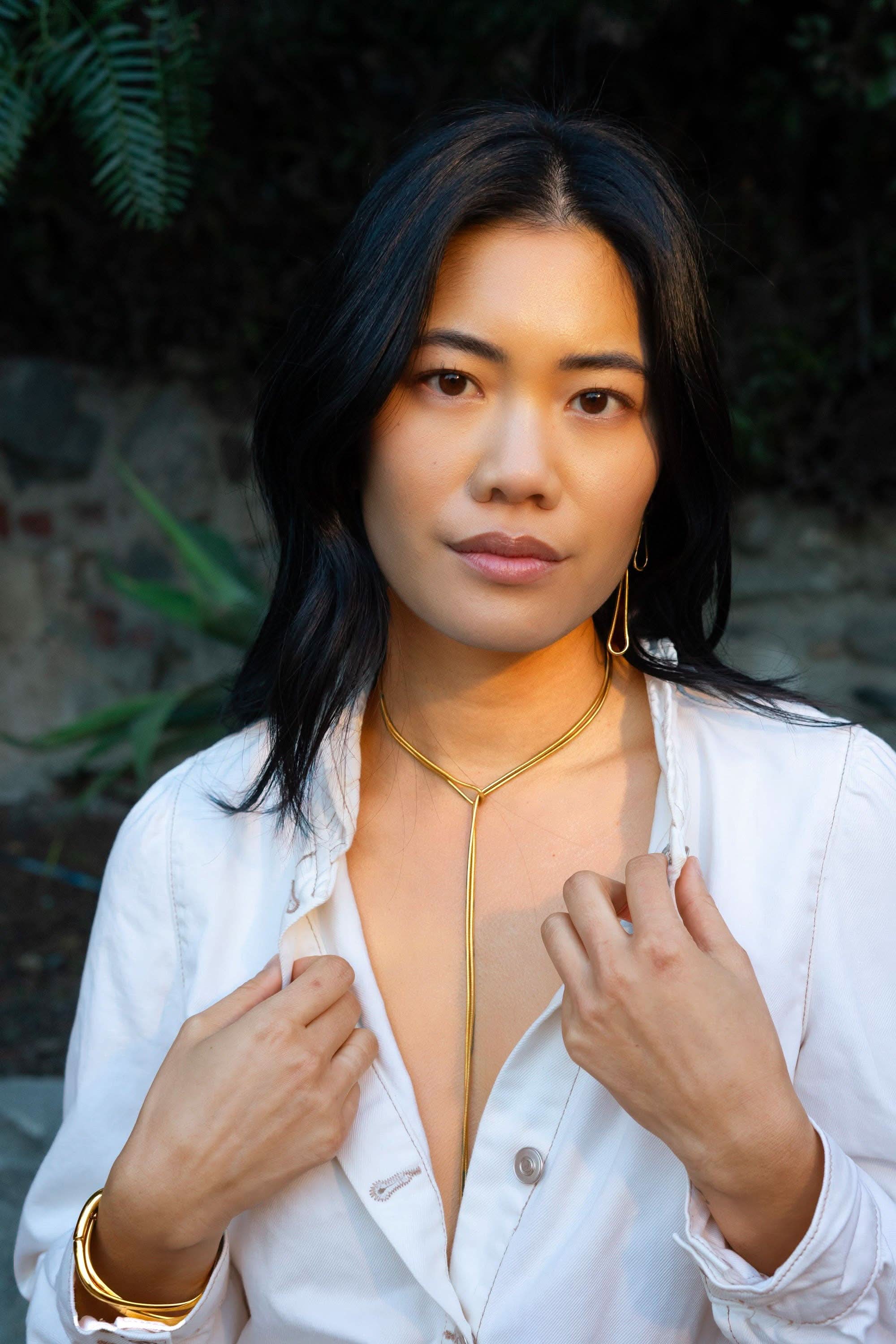 Woman wearing a white jacket with a gold trim, standing outdoors.
