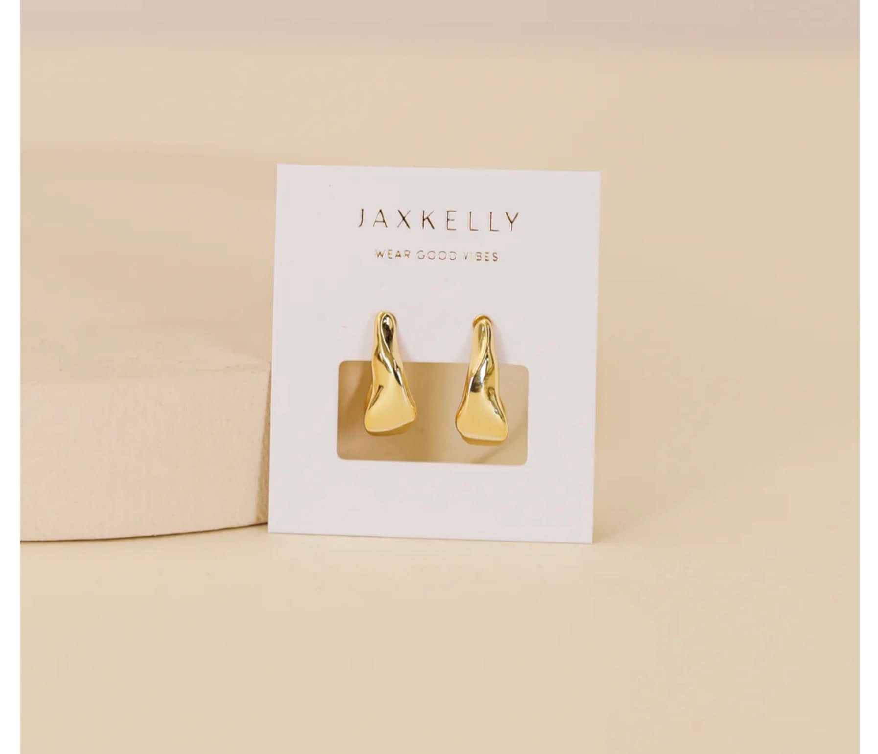 Gold earrings on a Jaxkelly branded card against