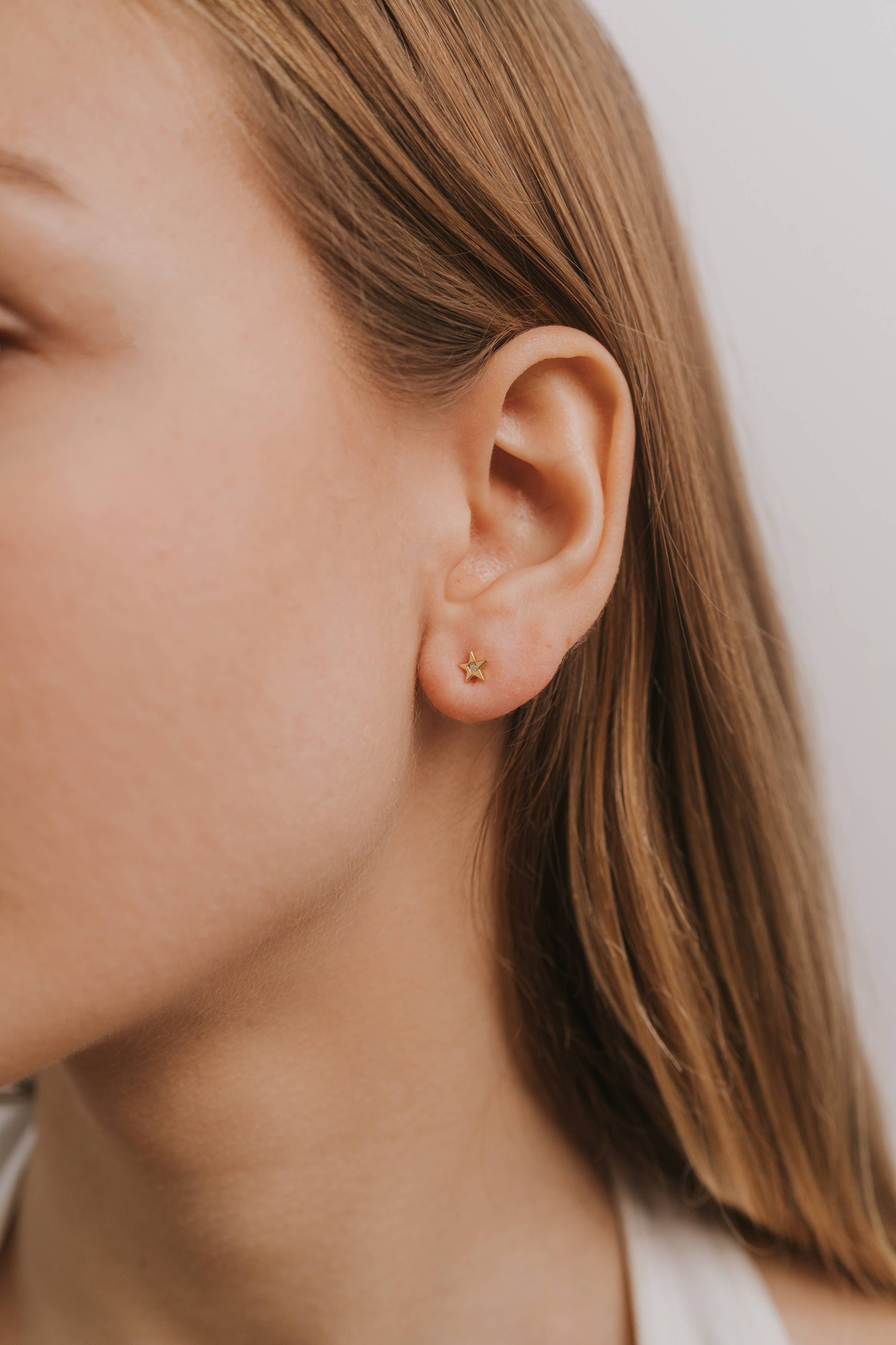 Close-up of a person wearing a star gold earring