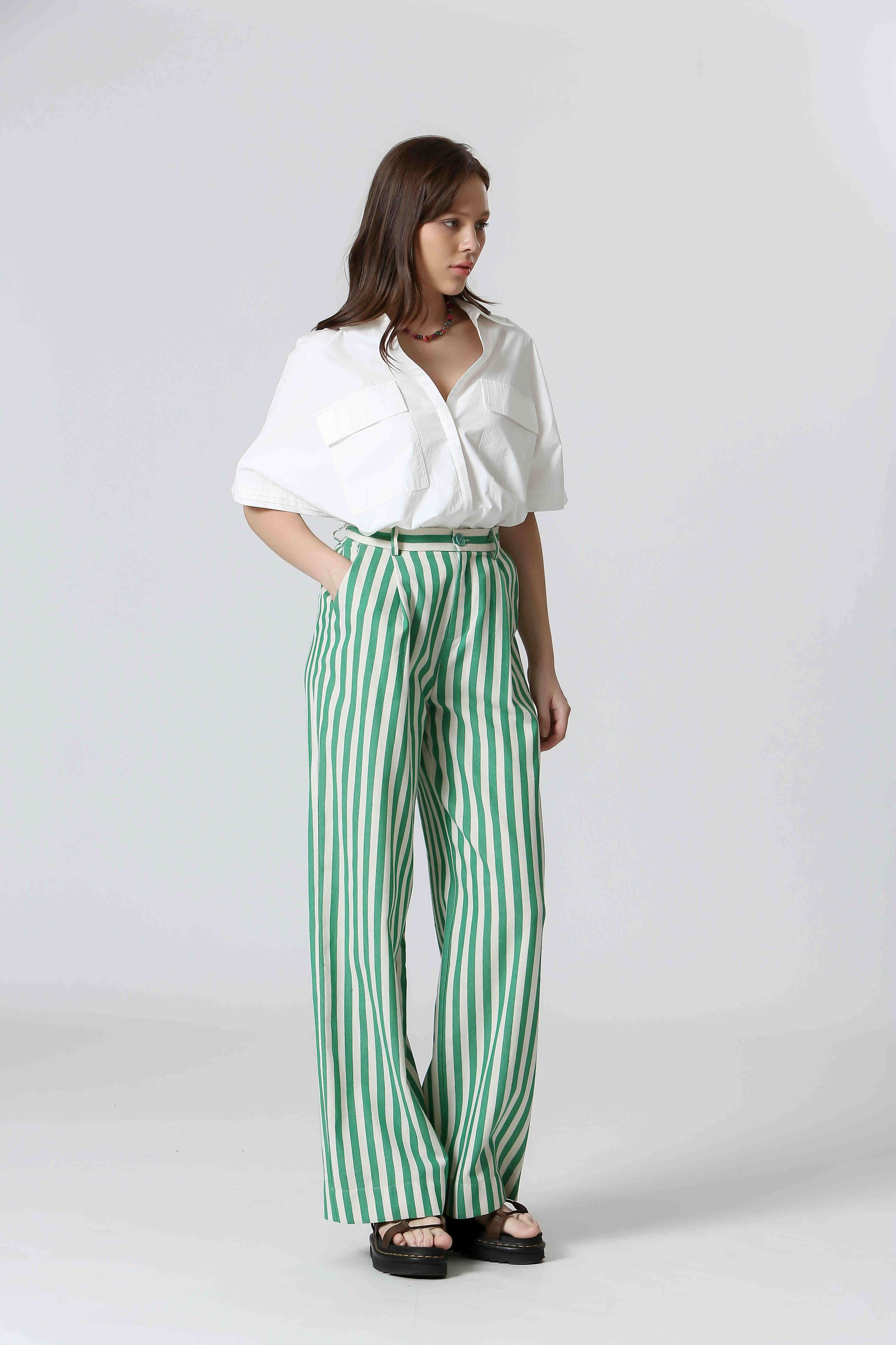 Woman wearing white shirt and green and white, vertically striped pants 