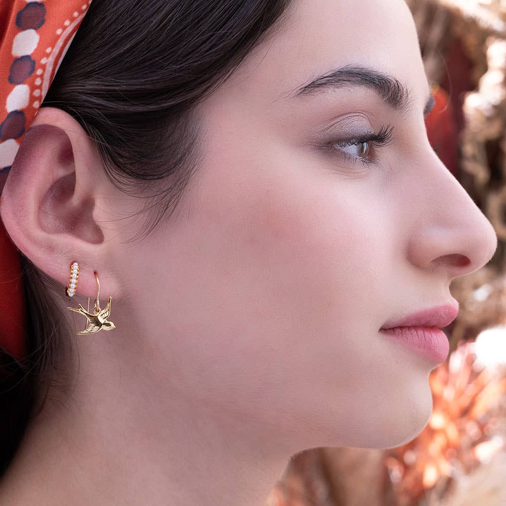 Swallow Bird Drop Earringsglod Close-up of two shiny, gold drop earrings.