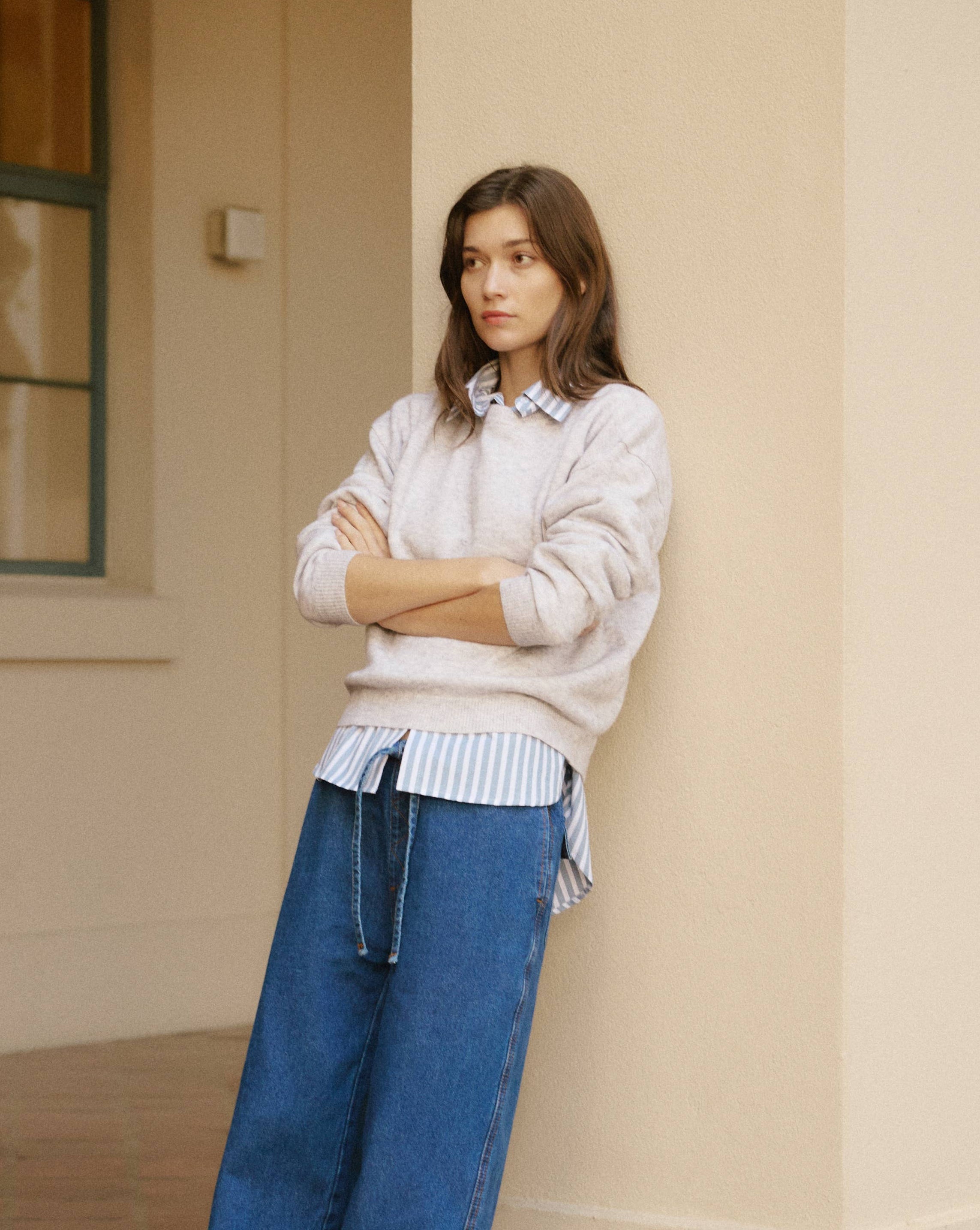 Woman wearing a light sweater and blue jeans standing 