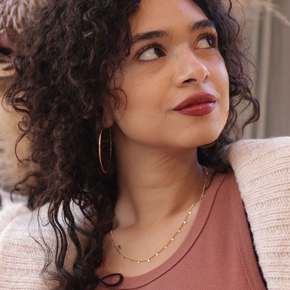 Woman wearing gold chain with tiny gold dots spaced evenly  