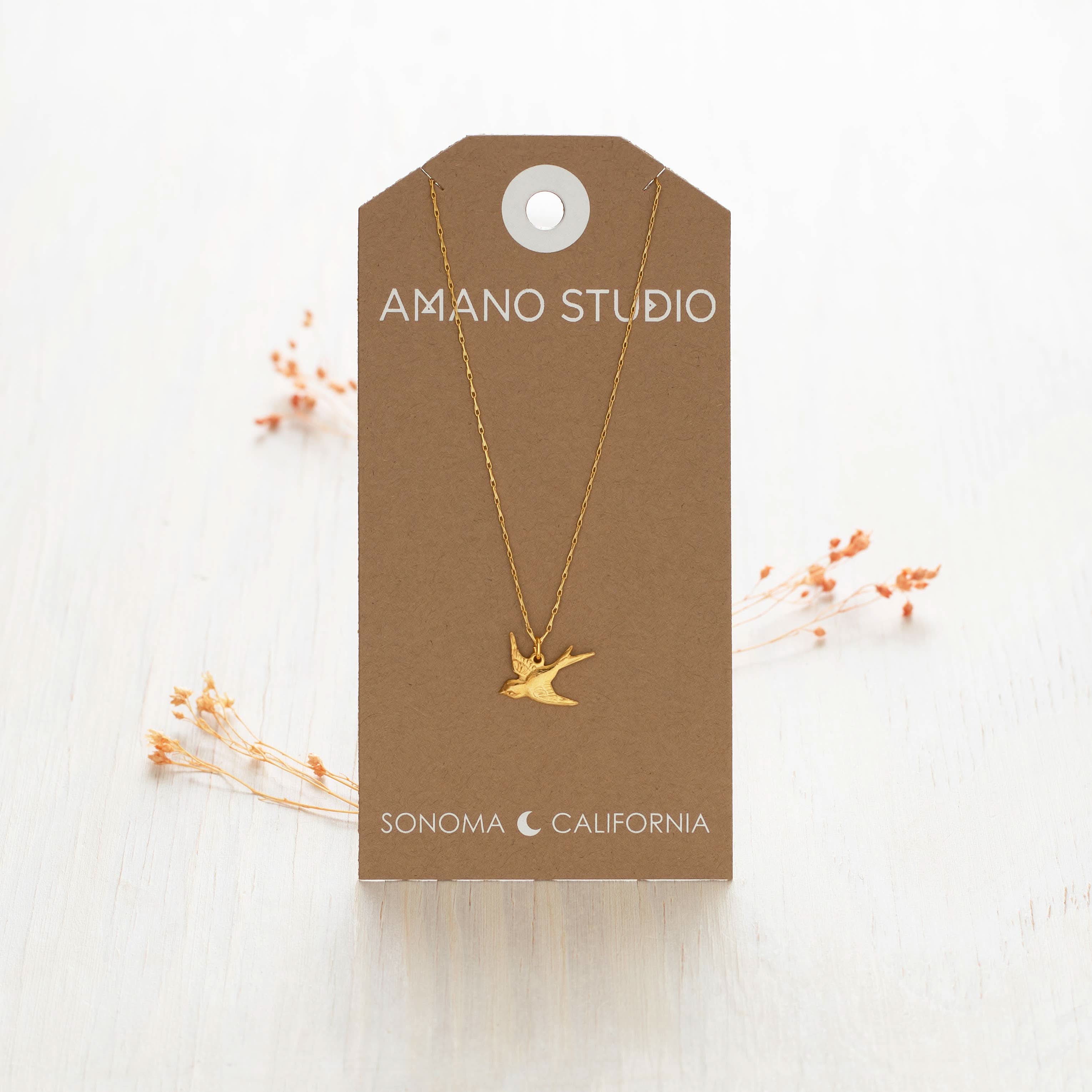Gold bird necklace on a brown Amano Studio card 