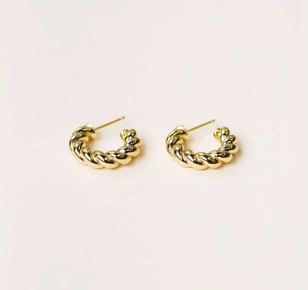 Pair of gold hoop earrings on a light beige background