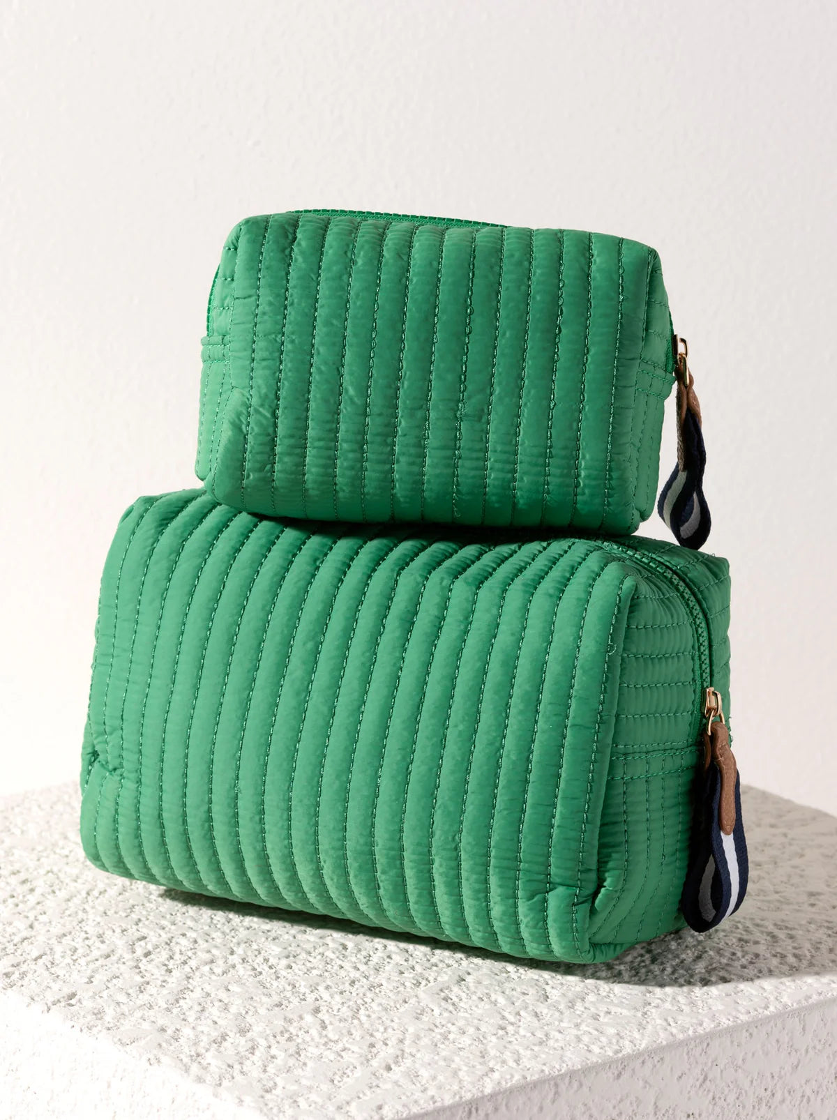 Two green textured bags stacked on a light background