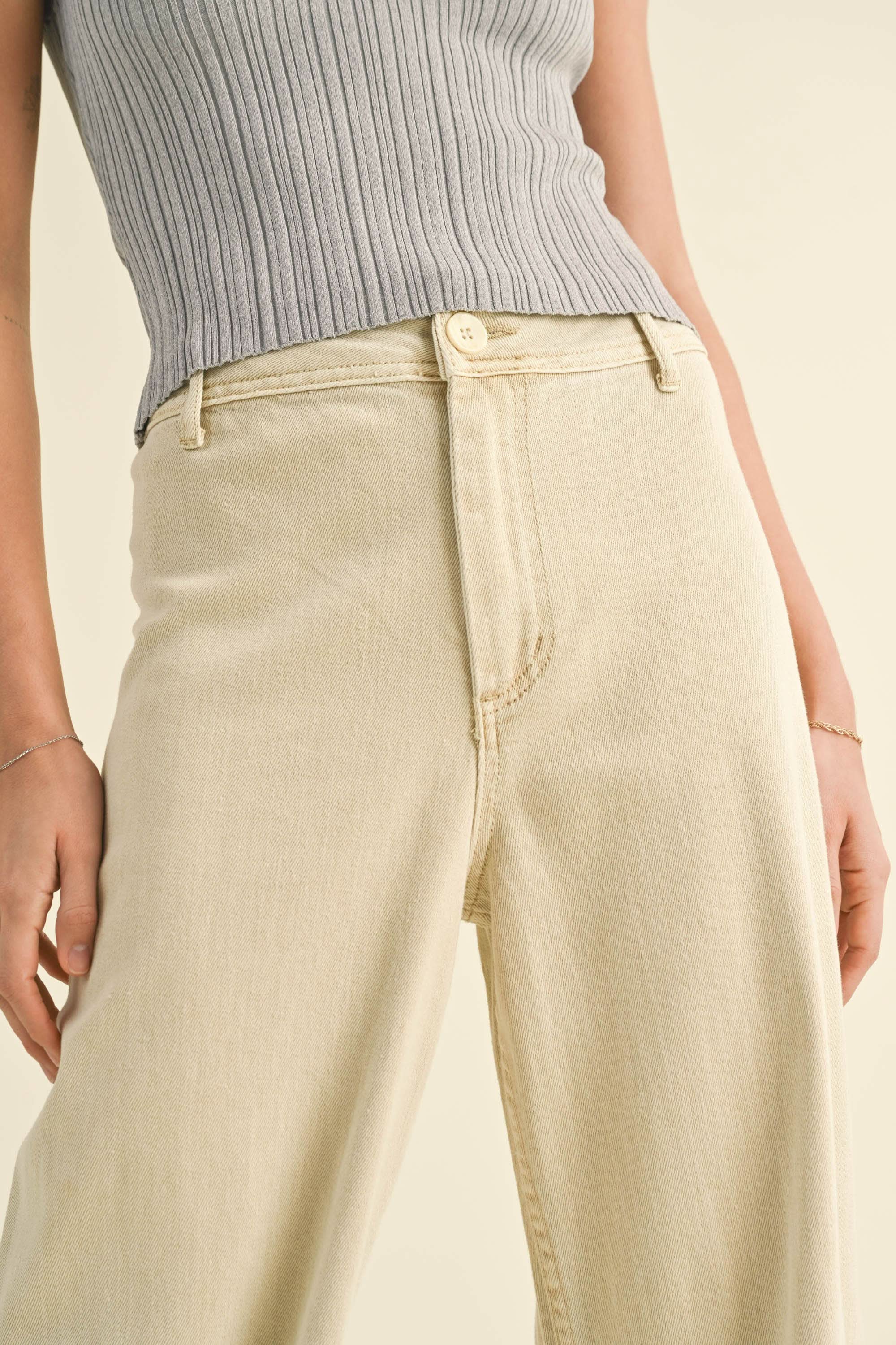 close up photo of Model wearing white wide leg denim pants with white button