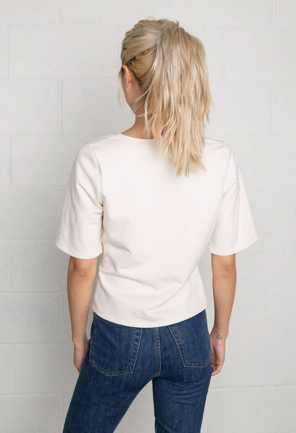 Woman wearing a cream wrap short sleeve shirt with blue jeans