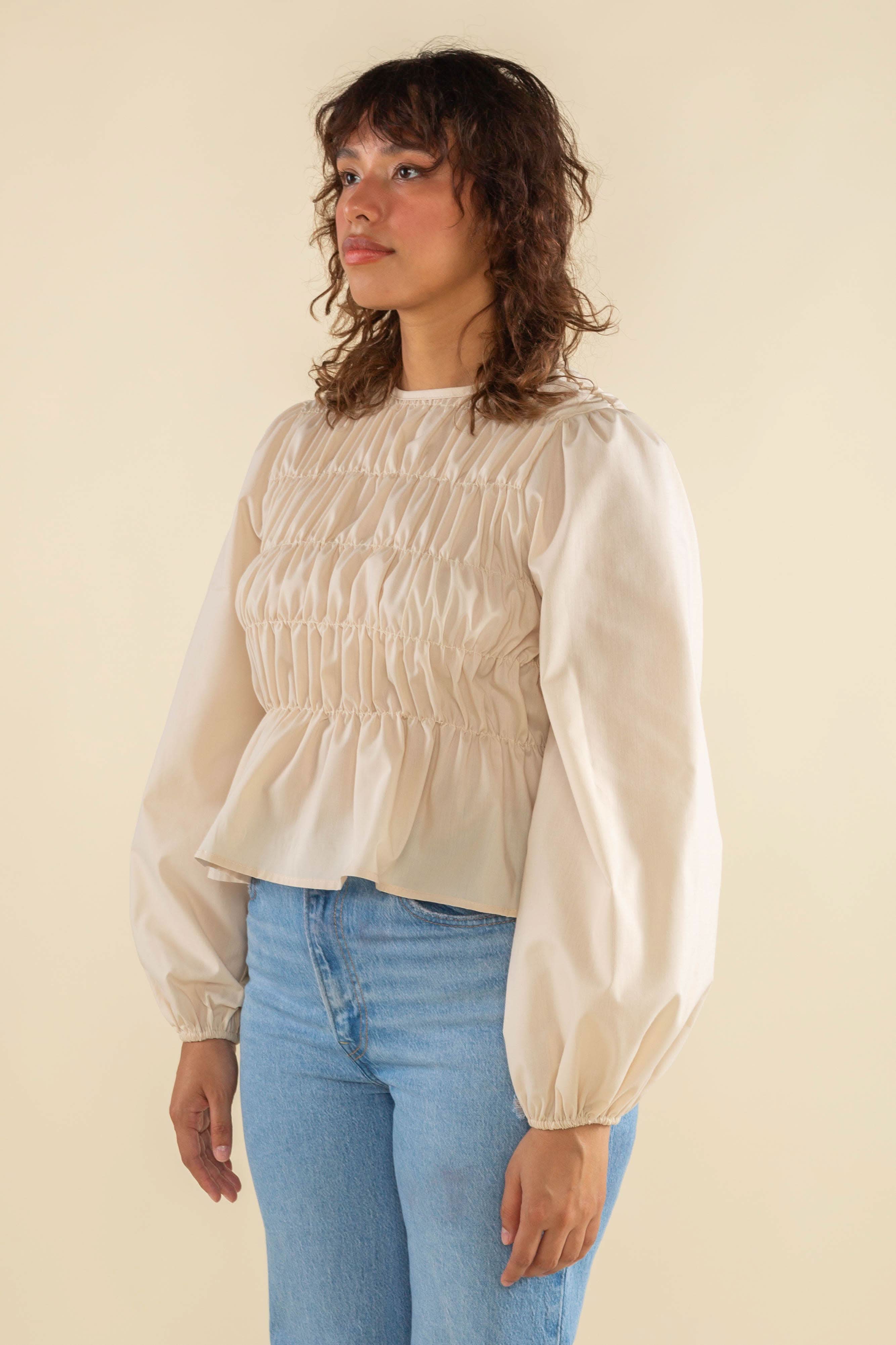 Woman wearing natural cream white color, bubble long sleeve, shirred, peplum style top