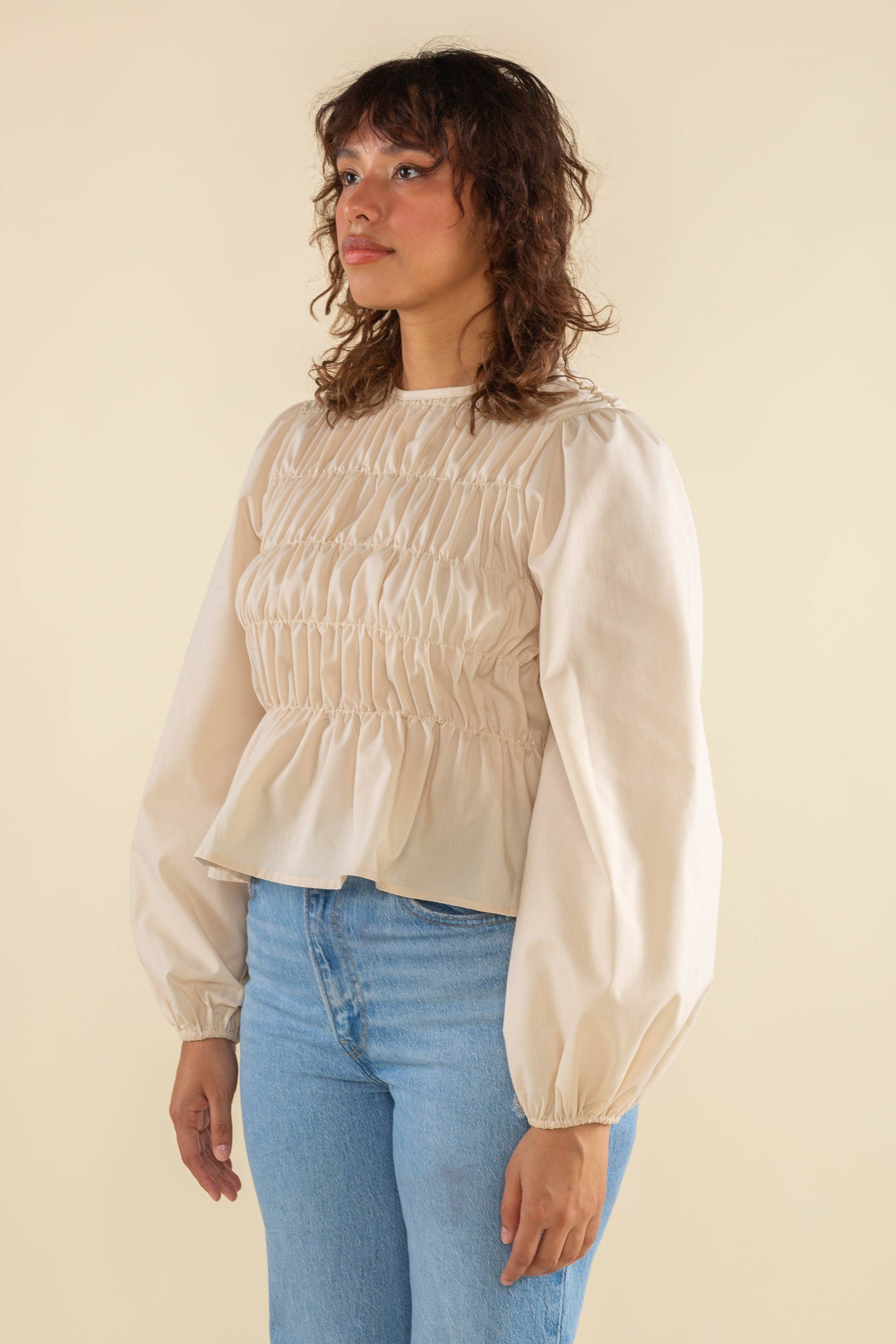 Woman wearing natural cream white color, bubble long sleeve, shirred, peplum style top