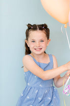 Child wearing Pair of gold and white quatrefoil flat back earrings laying on a white surface
