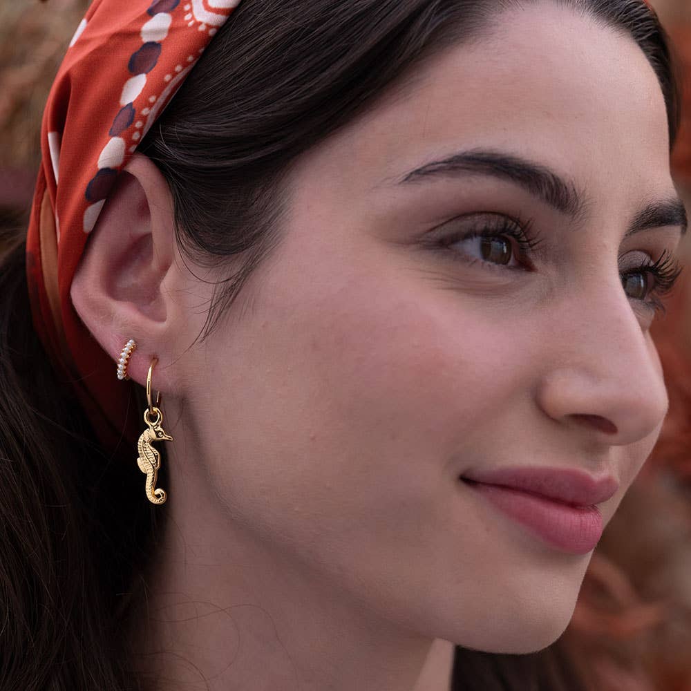 Close-up of a woman wearing a gold earring with a blurred background