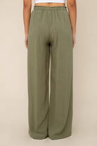 Woman facing away from the camera wearing Sage green, wide leg, cove linen pant and white tee
