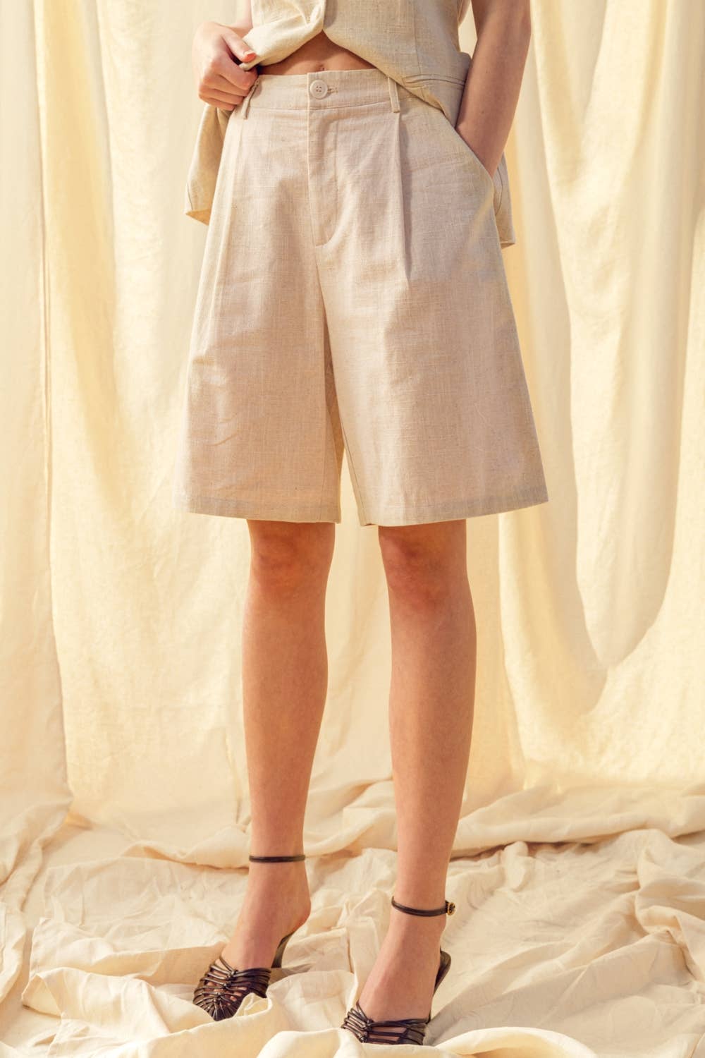 Person wearing beige shorts with a plain background