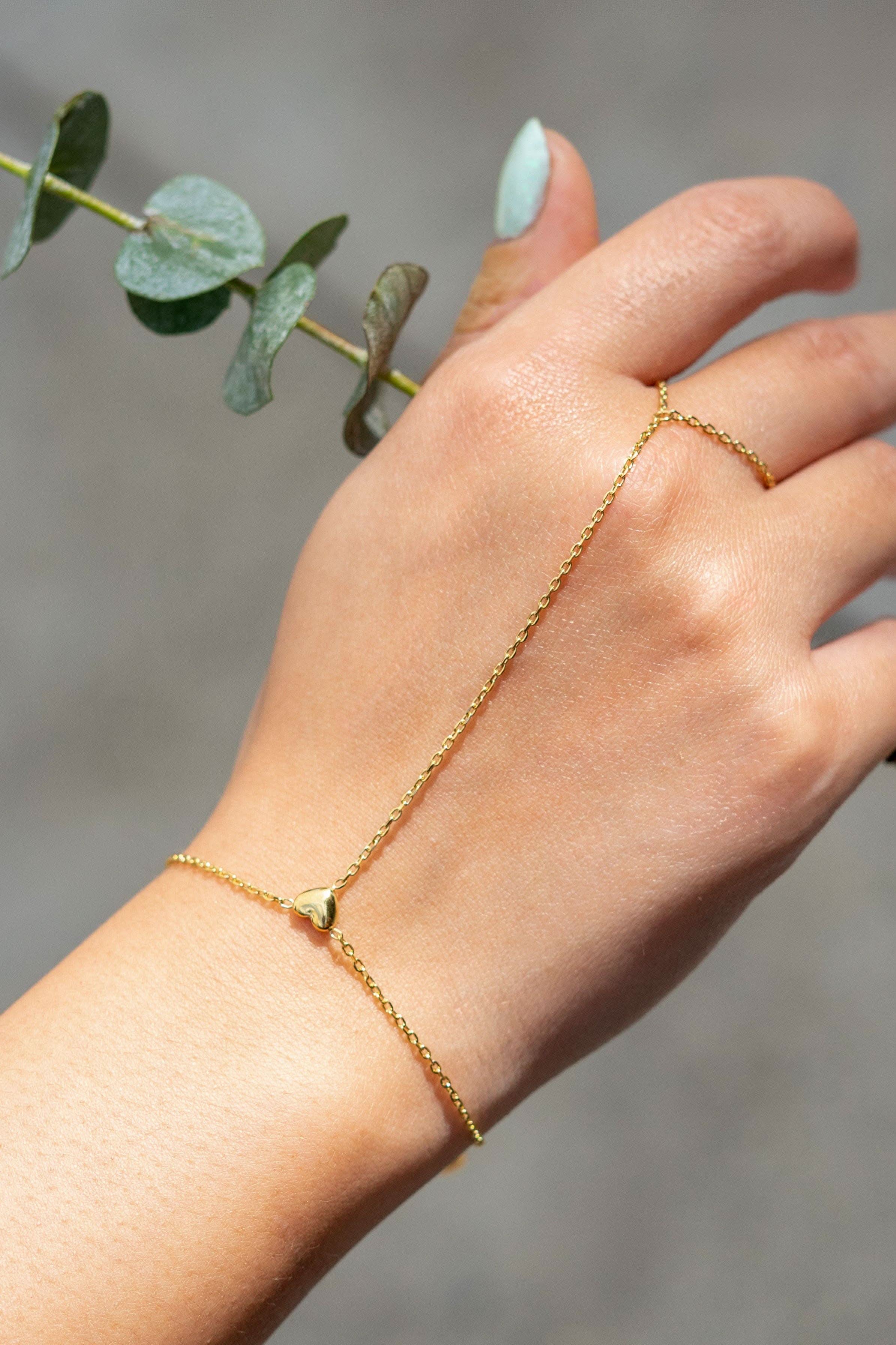 Delicate gold hand chain bracelet connected to a thin ring