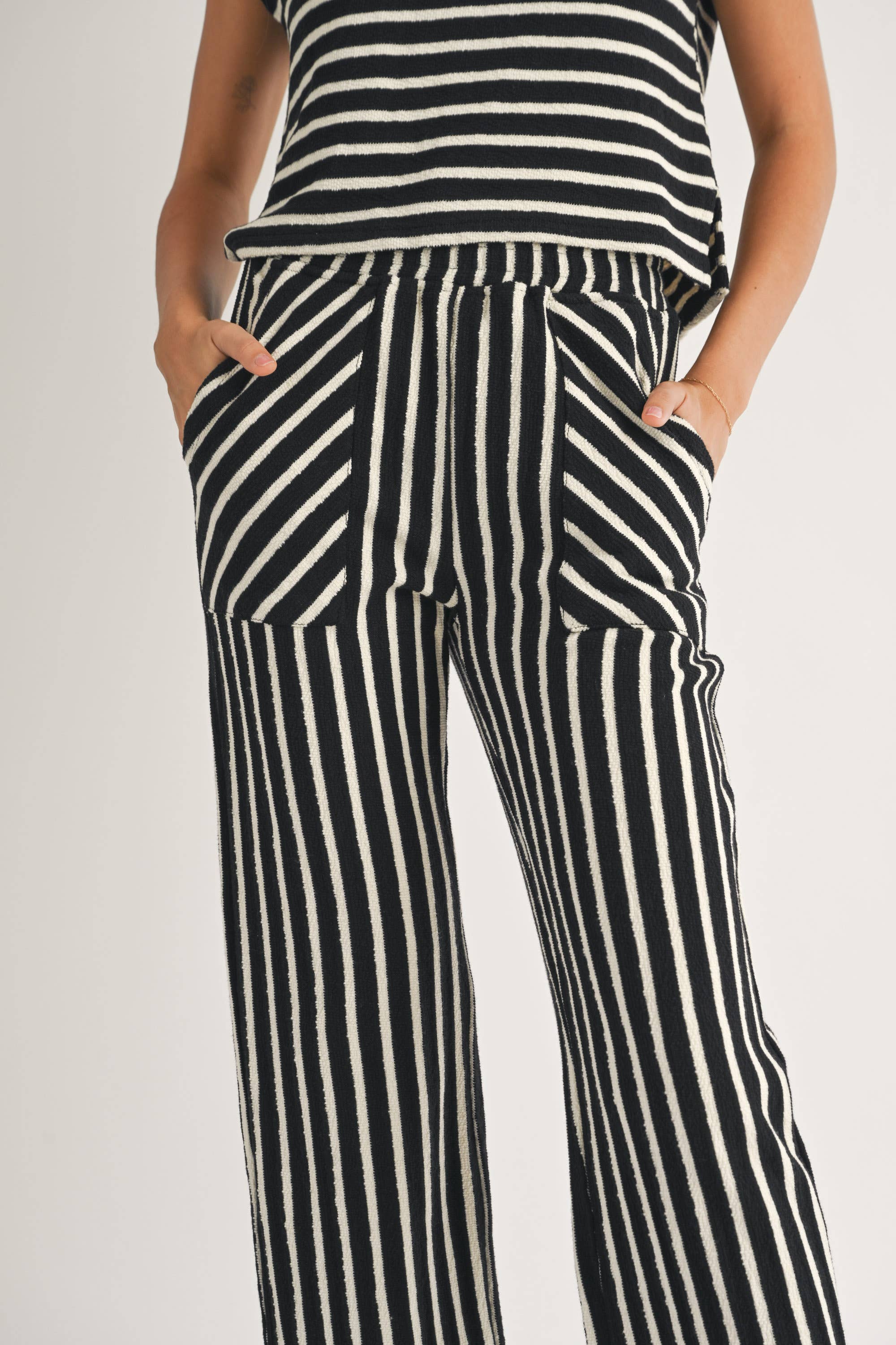 close up of woman wearing Textured vertical Stripe Knitted Pants with contrasting stripes in the front pockets made of 100% Cotton