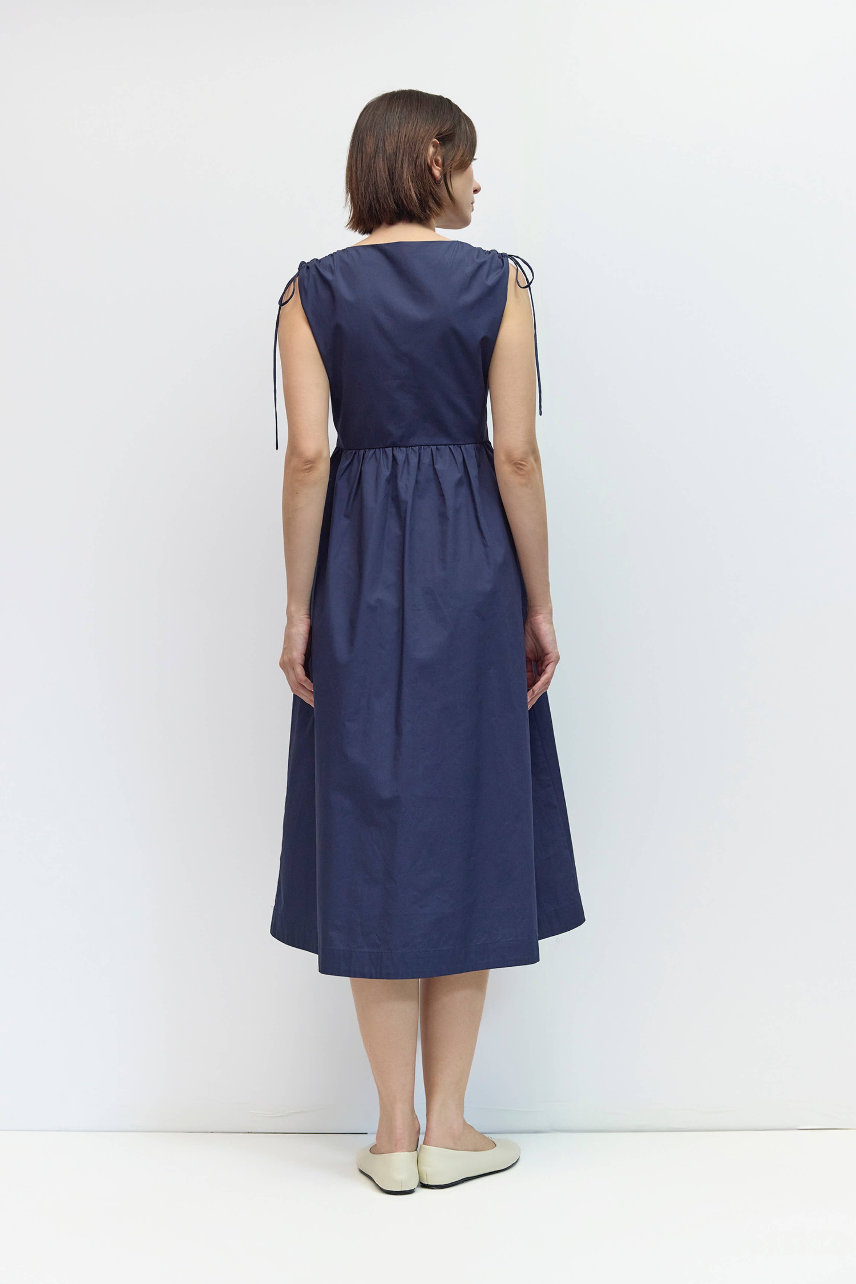 Woman wearing a navy blue dress against a white background
