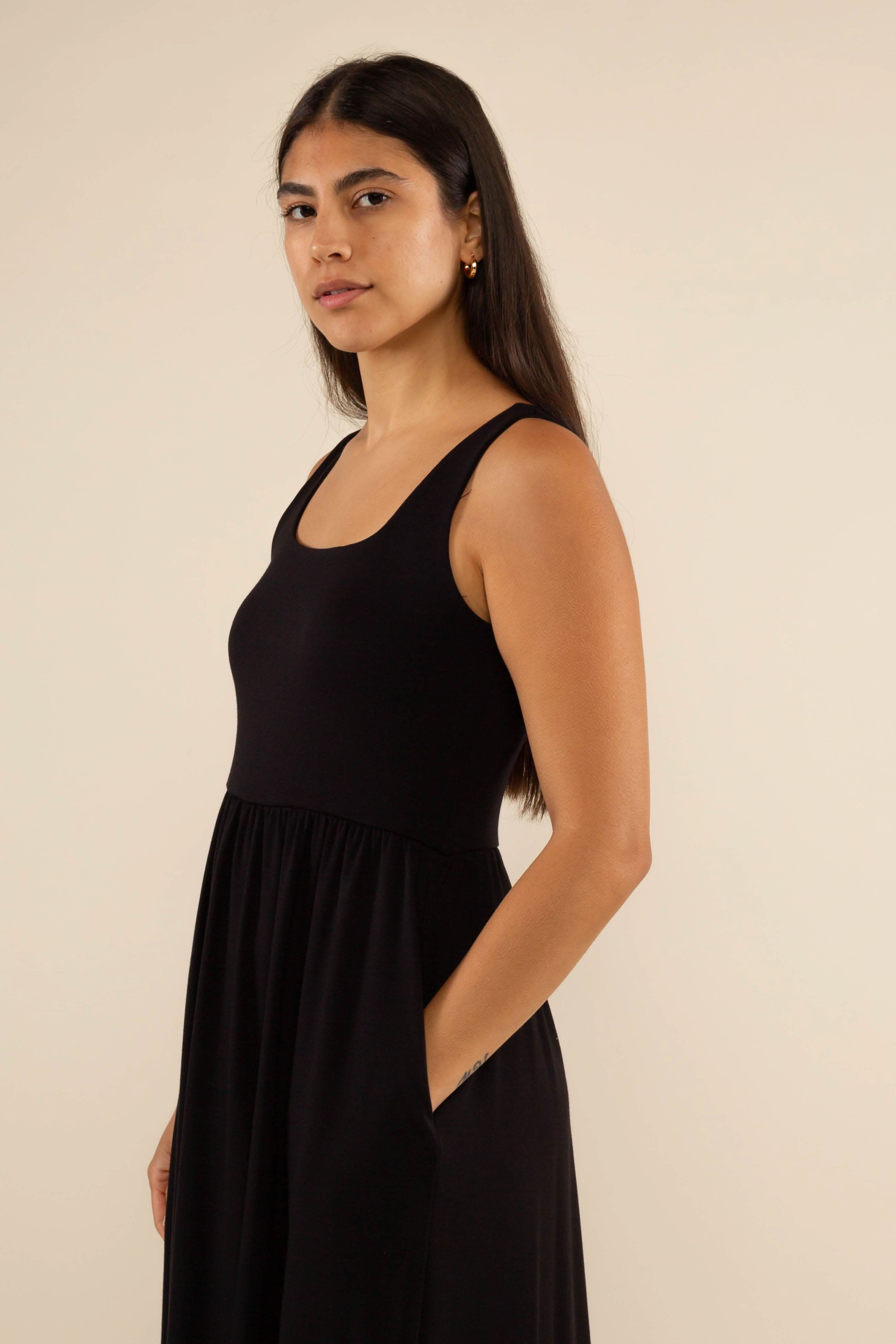 Woman wearing a black sleeveless dress against a beige background