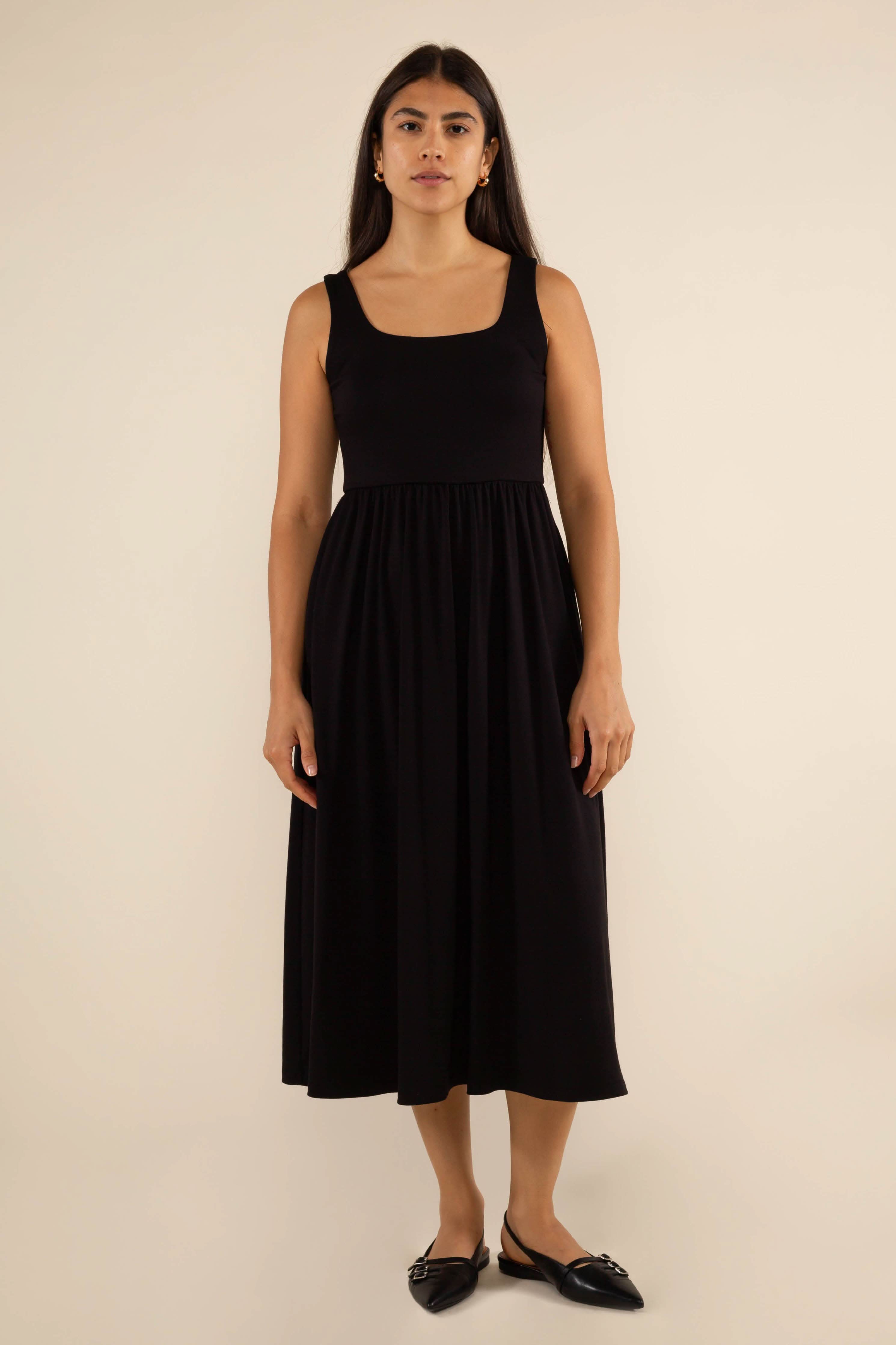 Woman wearing a black sleeveless dress against a beige background