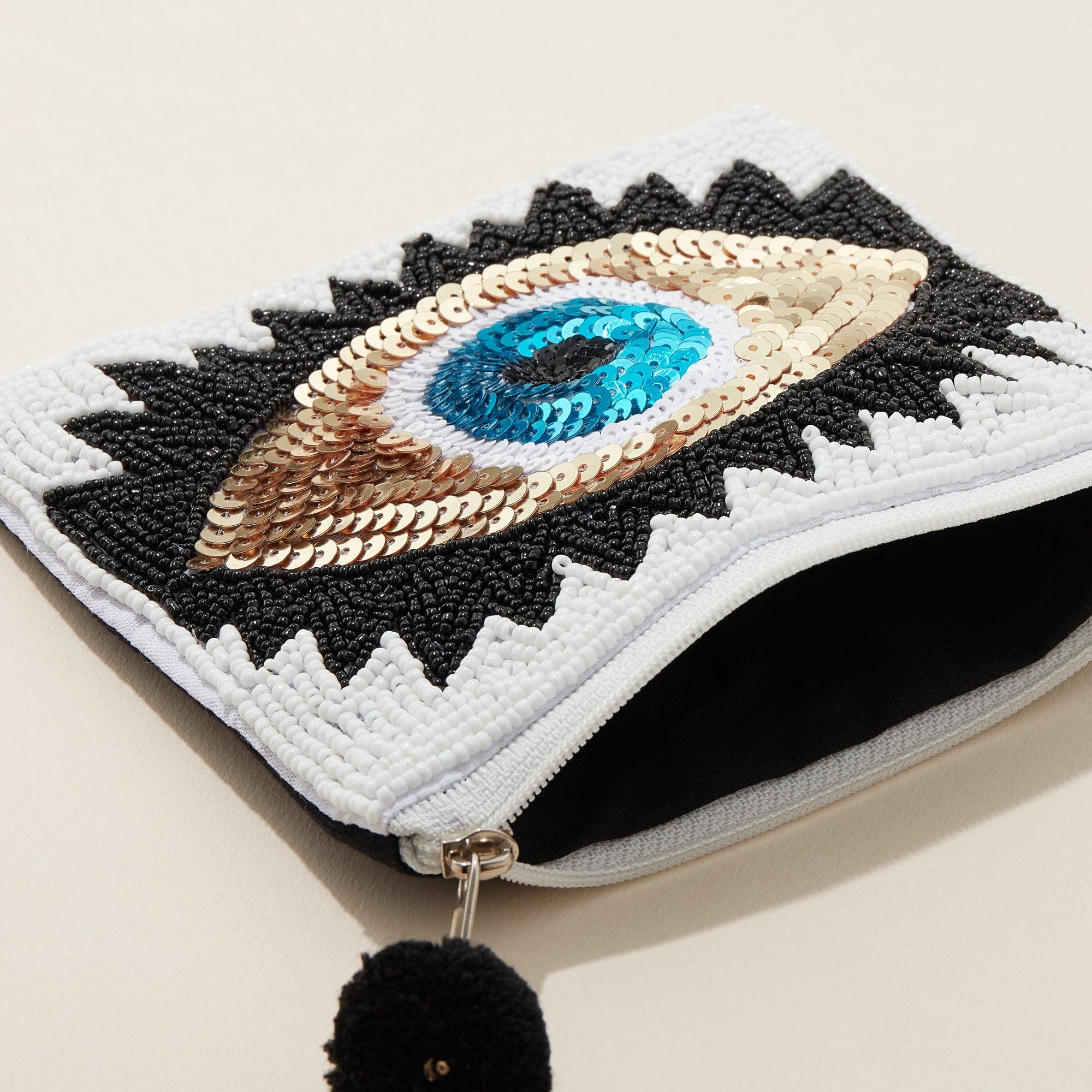 Embroidered pouch with eye design on a beige background