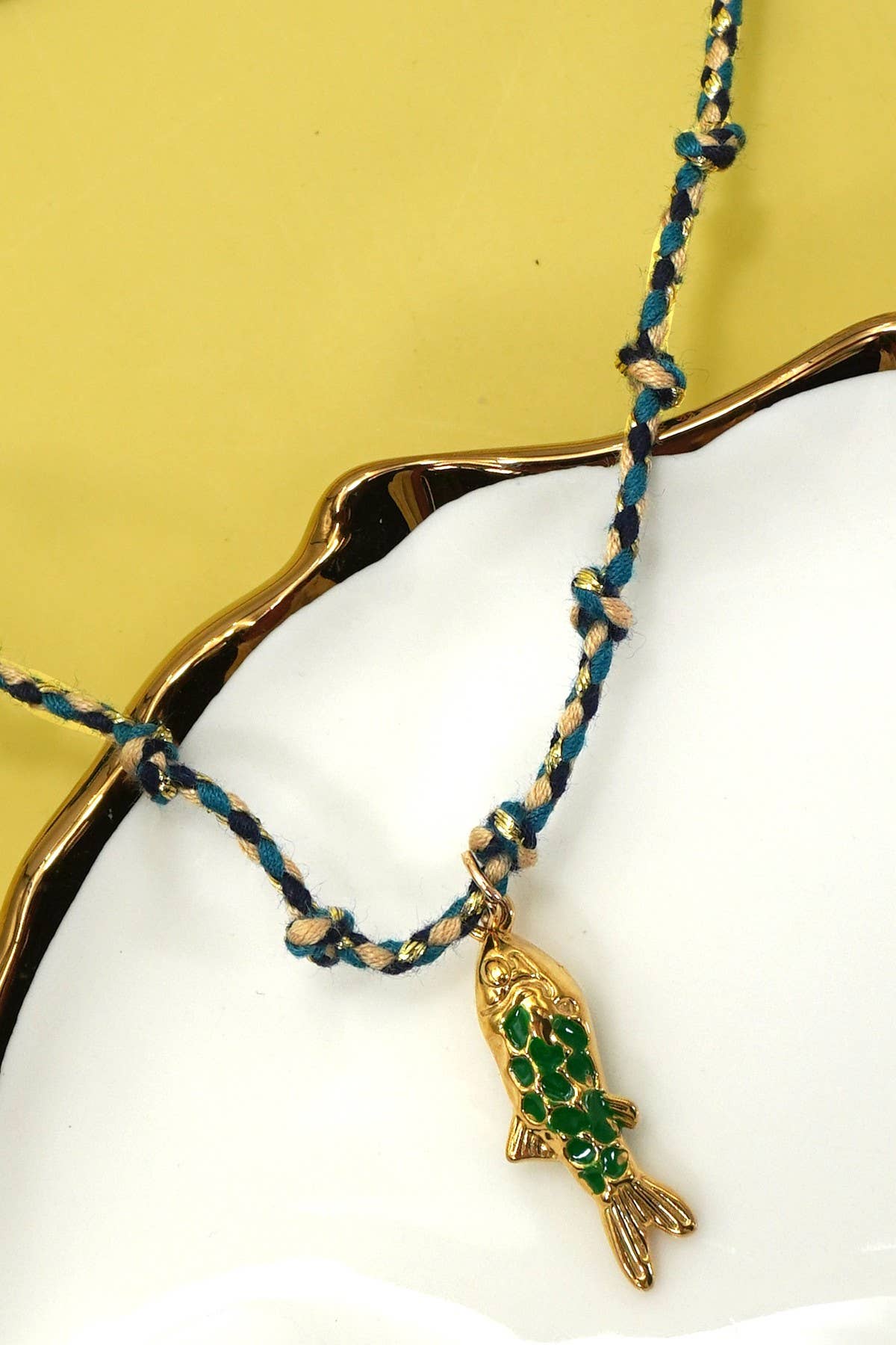 Necklace with green fish pendant on a yellow background