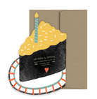 Slice of cake card on a plate with a brown envelope. 