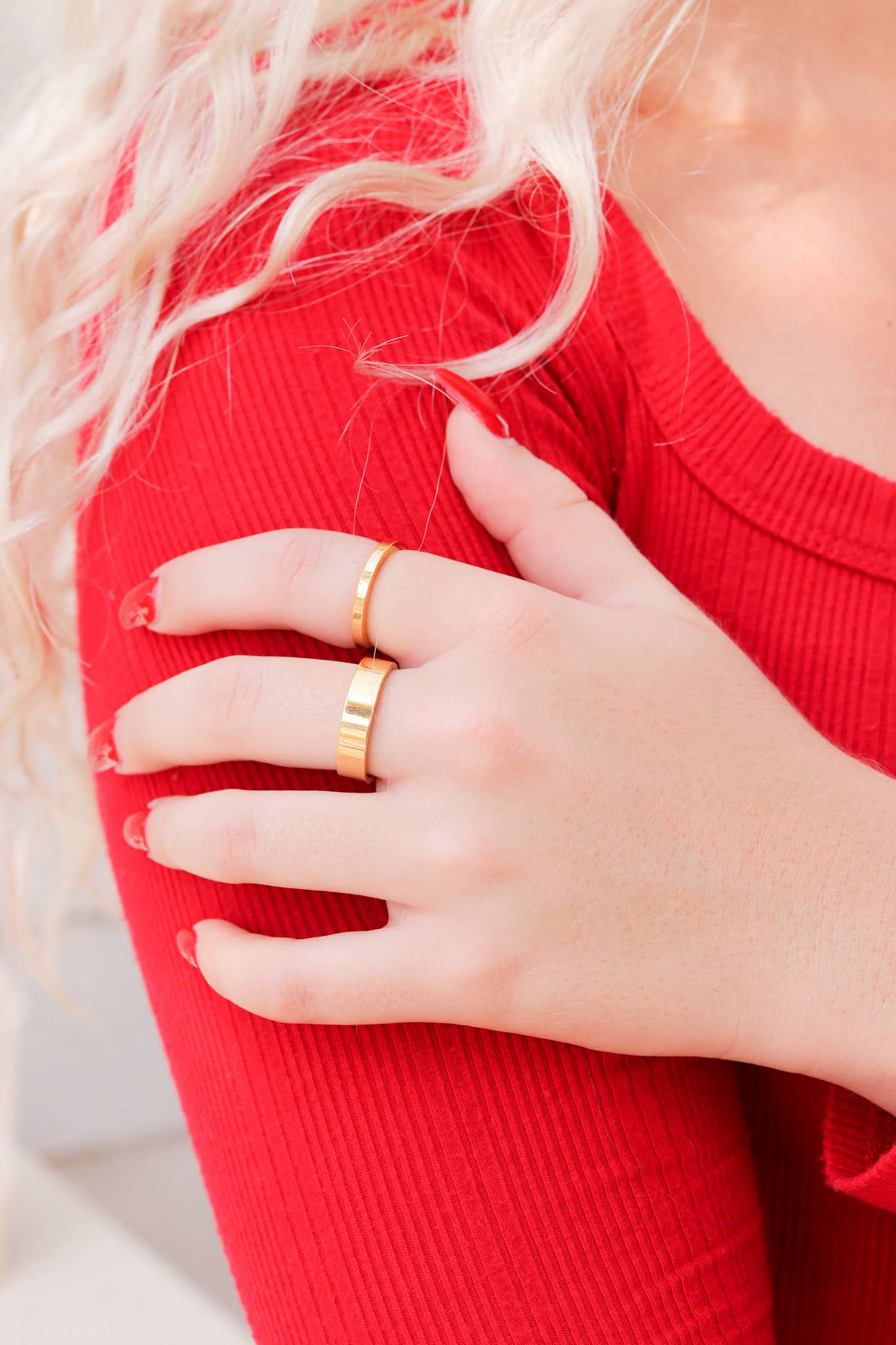 Person wearing a gold ring on a red garment with a blurred background