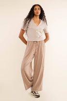 Woman wearing oat colored, ribbed, button down, short sleeve blouse top and beige pants 