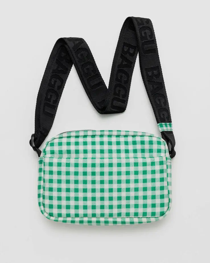 Green gingham BAGGU crossbody camera bag with black adjustable strap laying flat on a white background. 