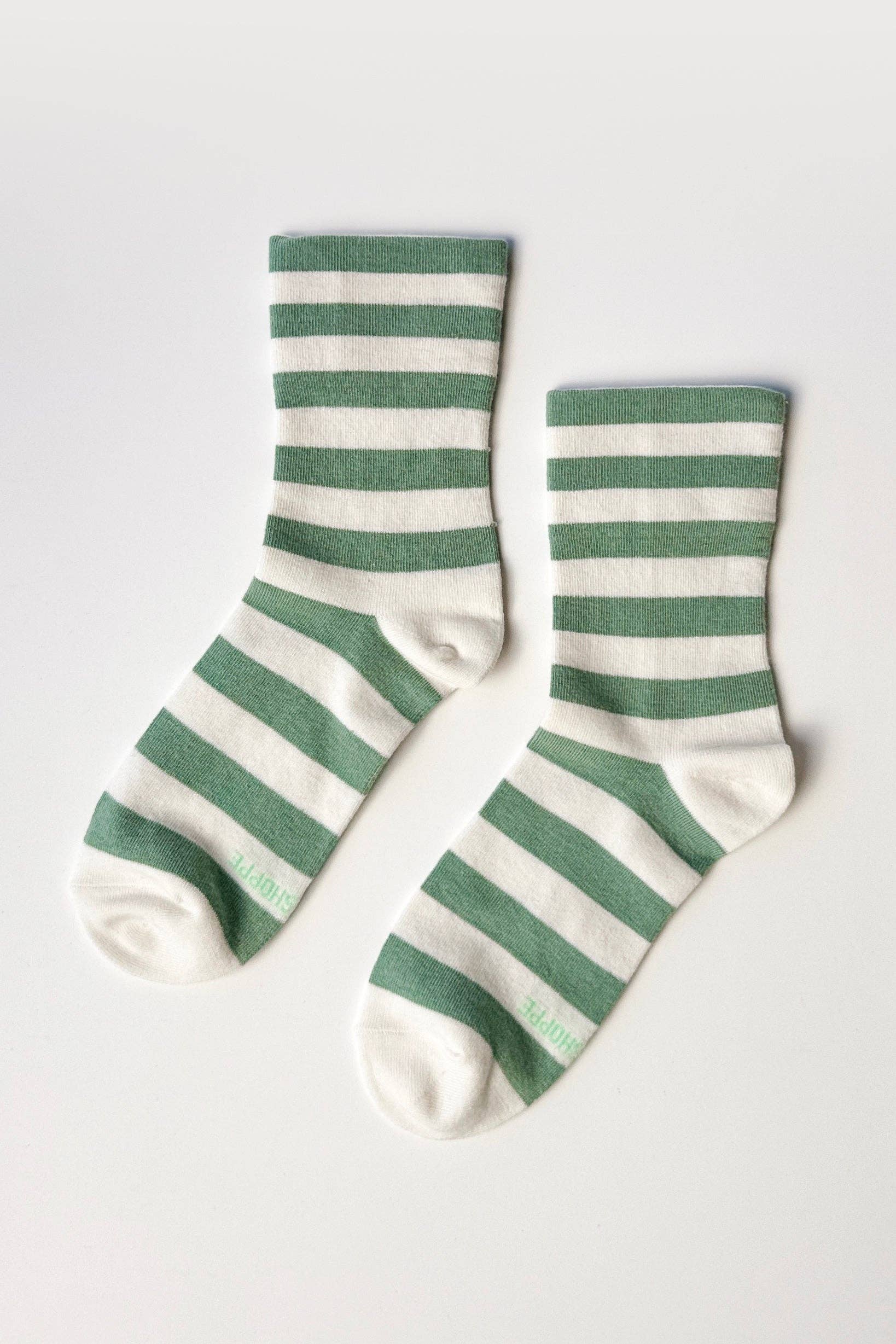 Pair of green and white striped socks on a light gray background