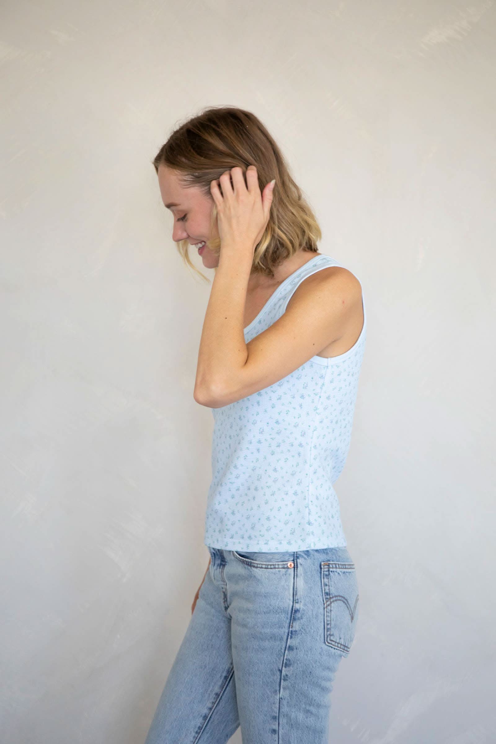 Woman wearing Waffle-knit henley tank top with a floral design in baby blue with blue jeans