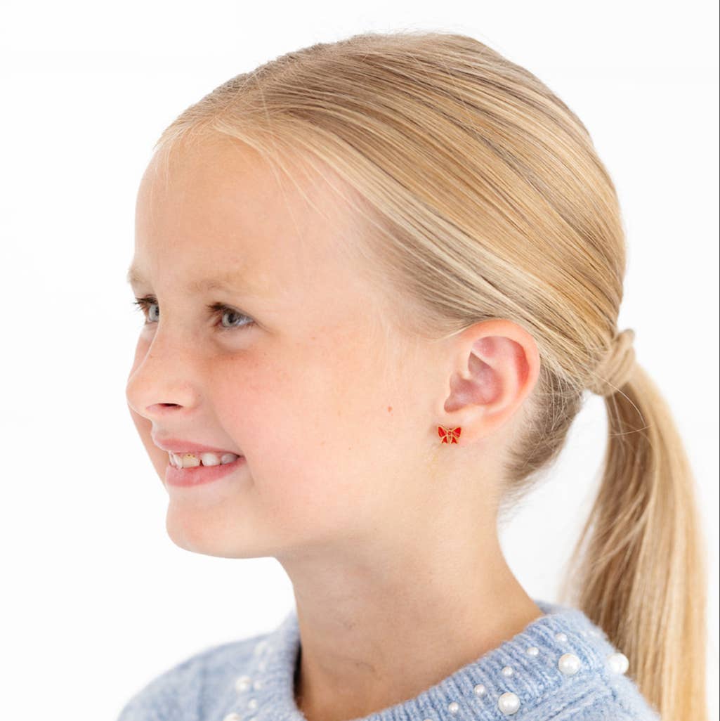 Young girl with blonde hair in a ponytail wearing butterfly-shaped earrings 