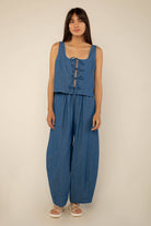 Woman wearing denim, high rise, barrel jeans with a medium wash color and matching top 