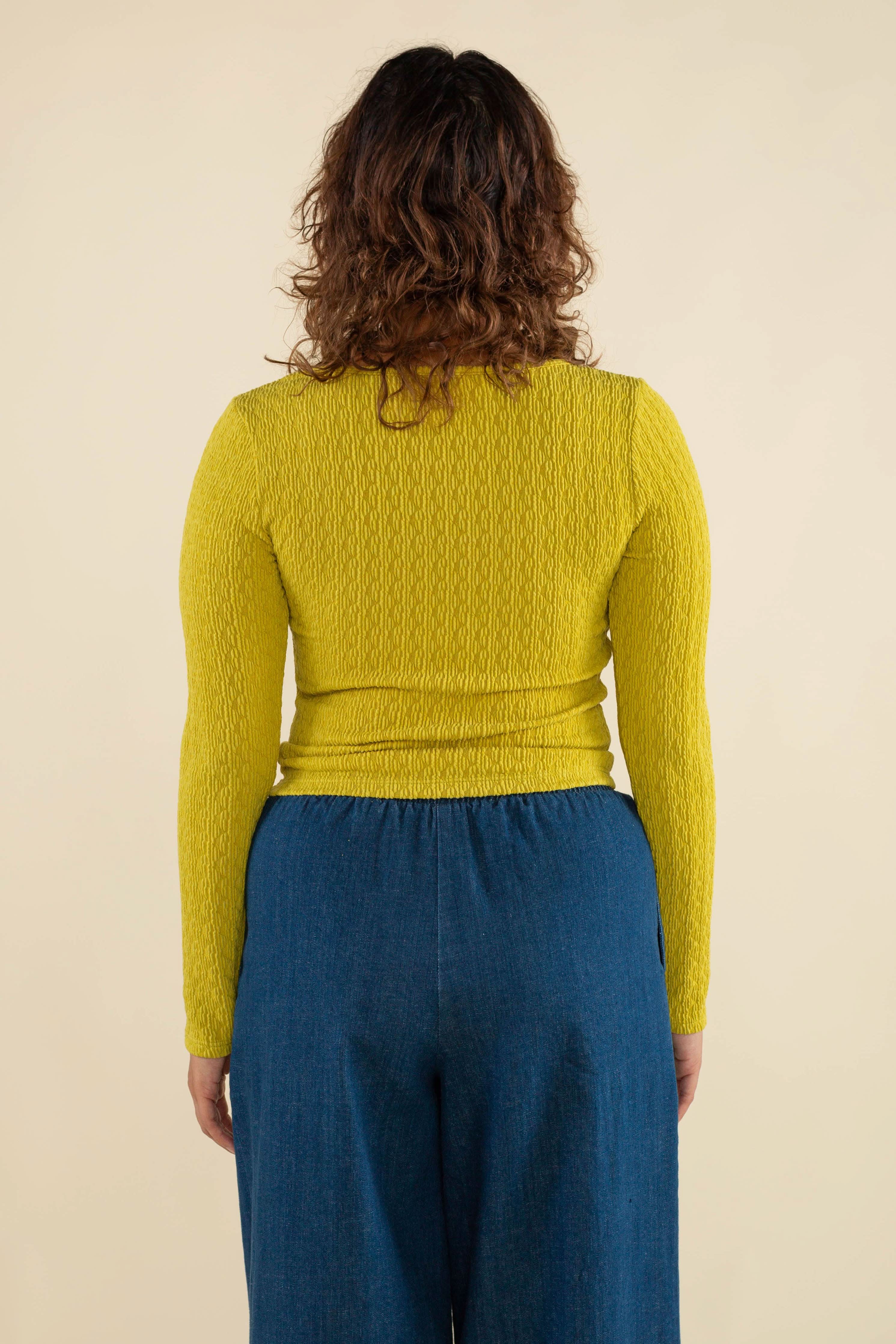 Woman wearing chartreuse, square neck line, textured, long sleeve top and jeans 