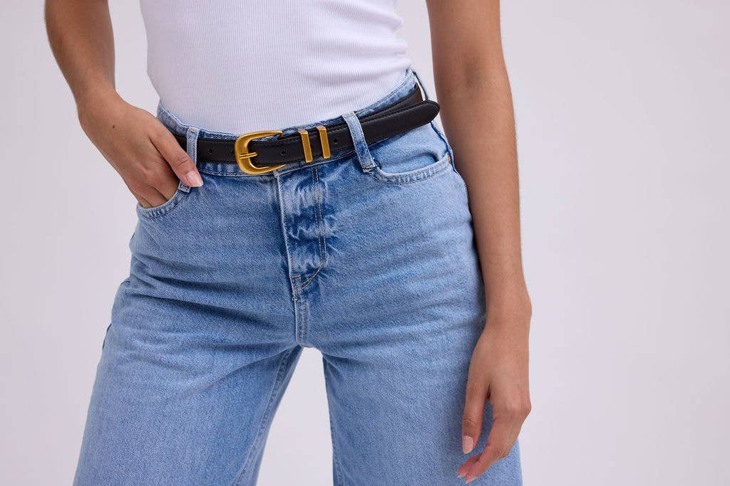 Person wearing blue jeans with a black belt on a plain background