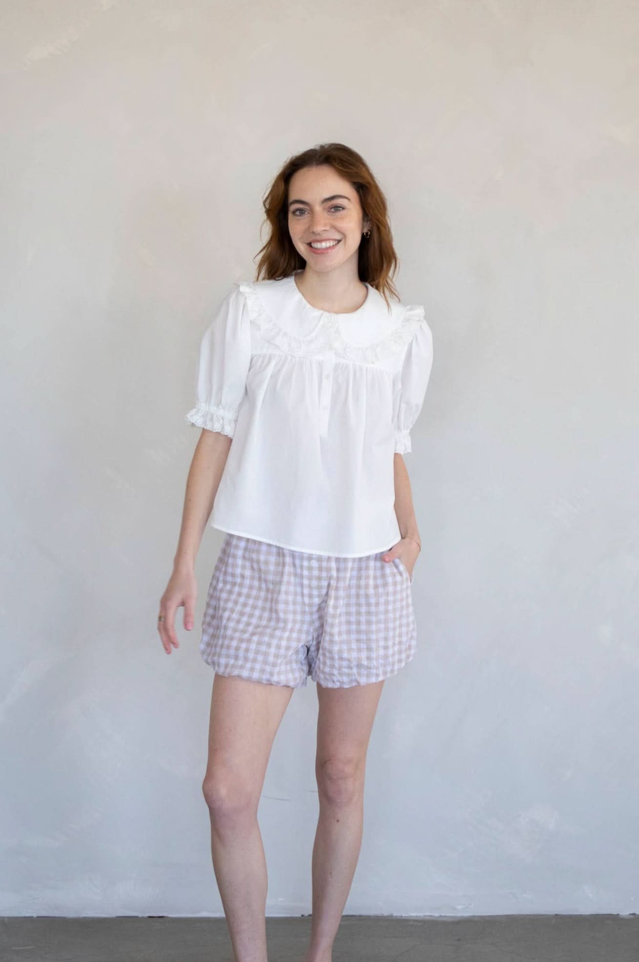 Woman wearing white half button dreamy sweetheart blouse and plaid shorts