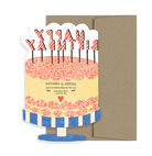 Yellow Happy Birthday cake with pink frosting and sprinkles card with a brown envelope. 